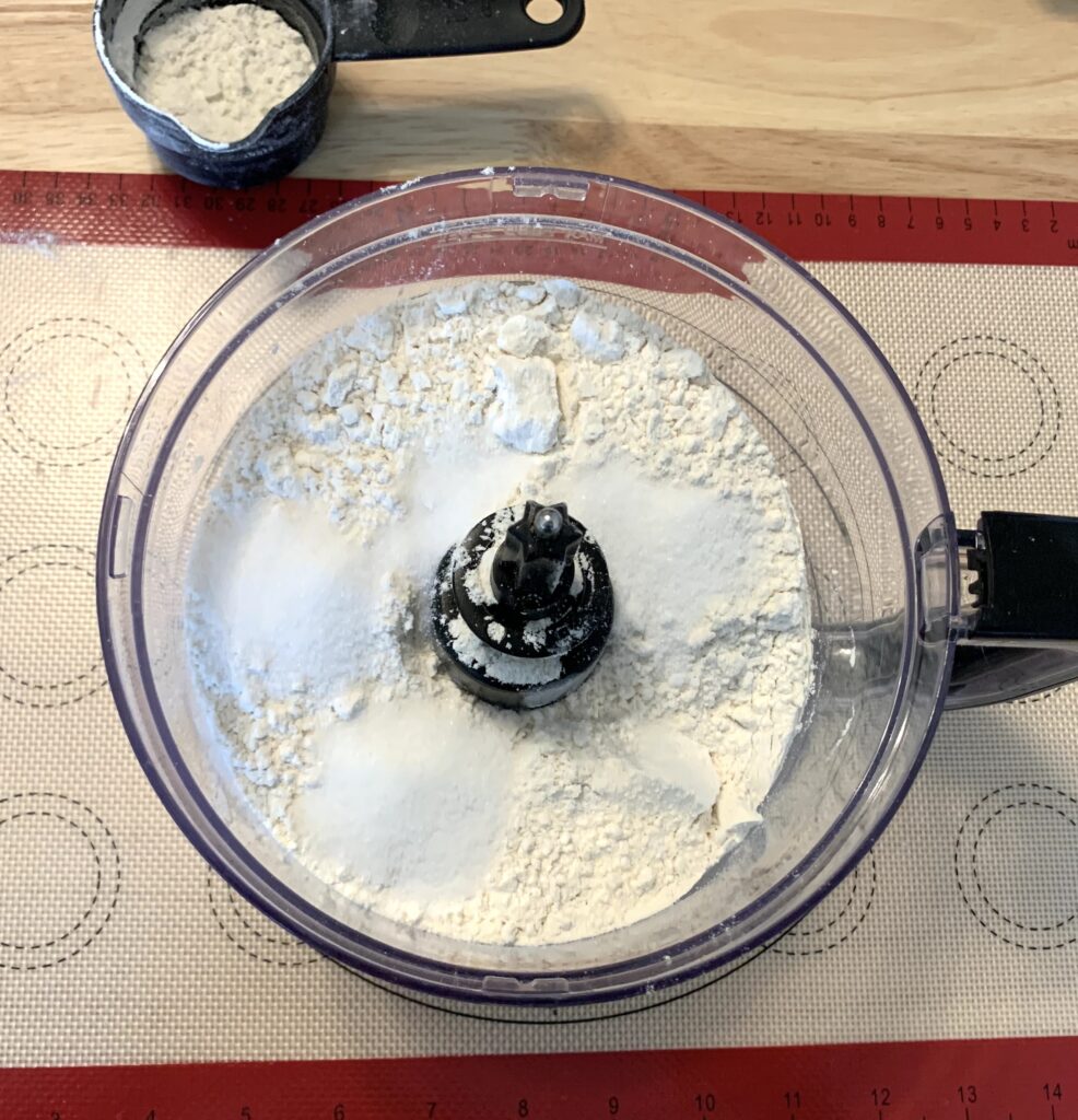 Flour, sugar, and salt in a food processor on silicone mat